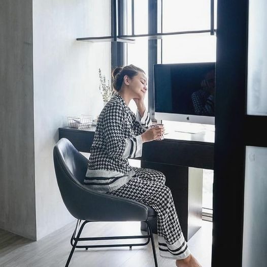 A woman sitting and wearing a silk long sleeve pajama set