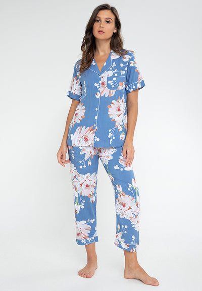 A woman standing and wearing a short sleeve pajama set in a floral design