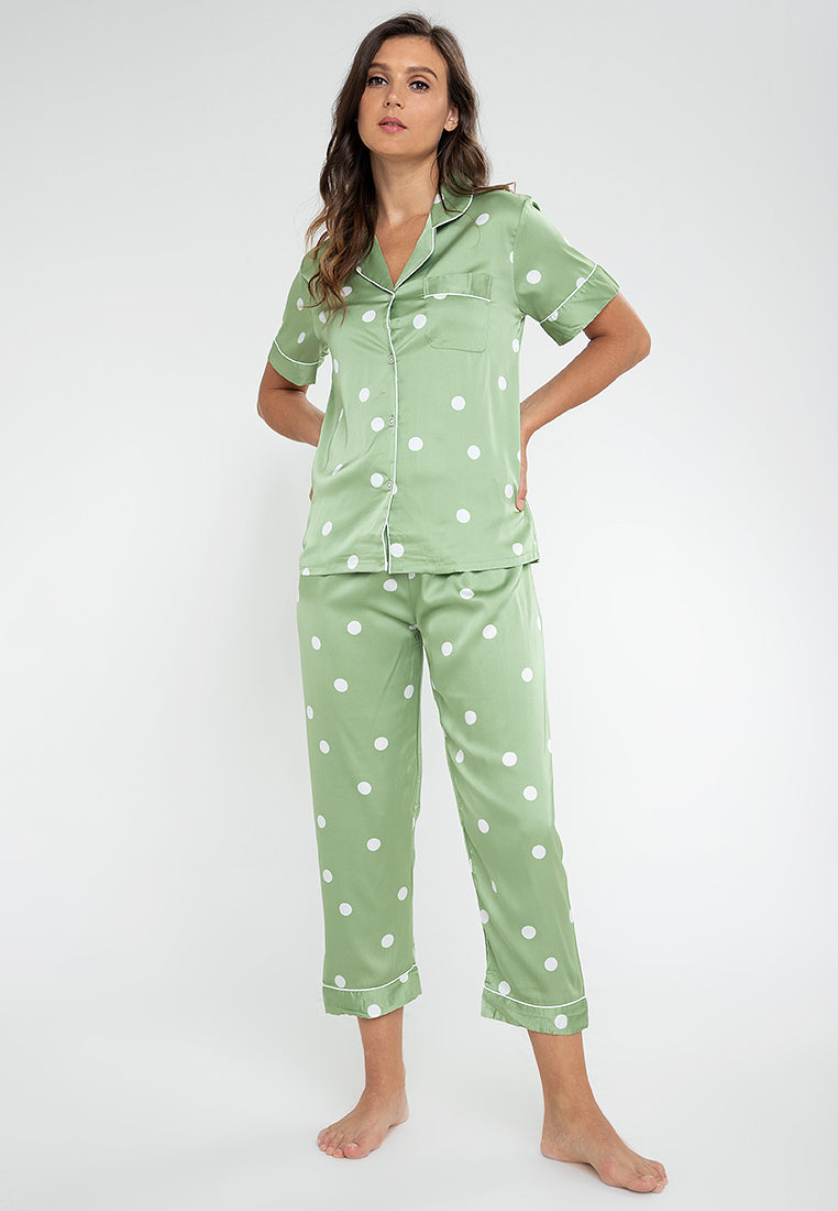 A woman standing and wearing a short sleeve pajama set in a polka dot design