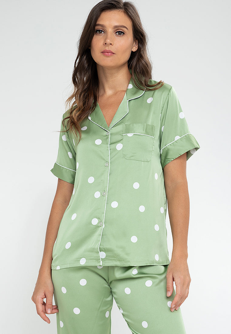 A woman standing and wearing a short sleeve pajama set in a polka dot design