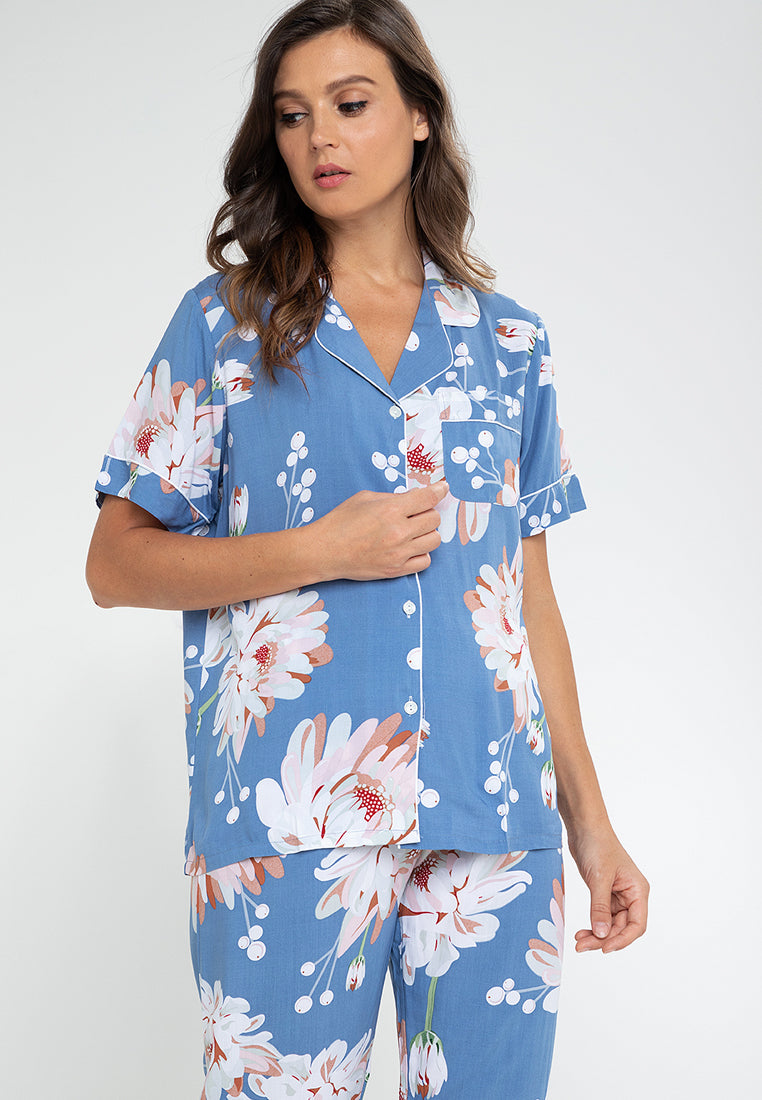 A woman standing and wearing a short sleeve pajama set in a floral design