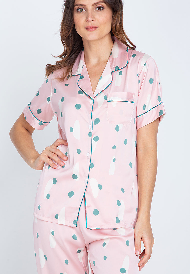 A woman standing and wearing a silk short sleeve pajama set