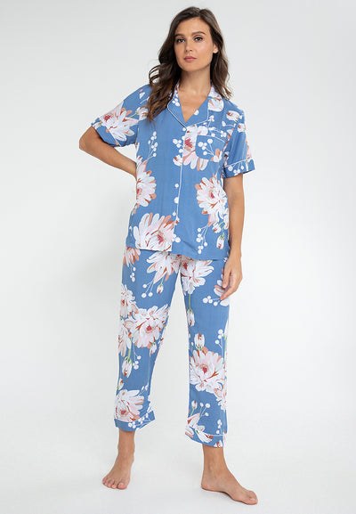 A woman standing and wearing a short sleeve pajama set in a floral design
