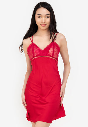 A woman standing and wearing a red Silk slip dress