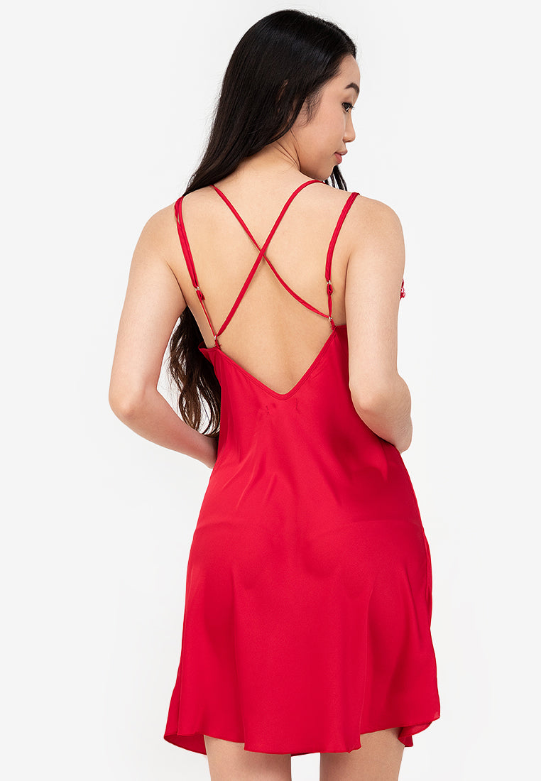 A woman standing and wearing a red Silk slip dress