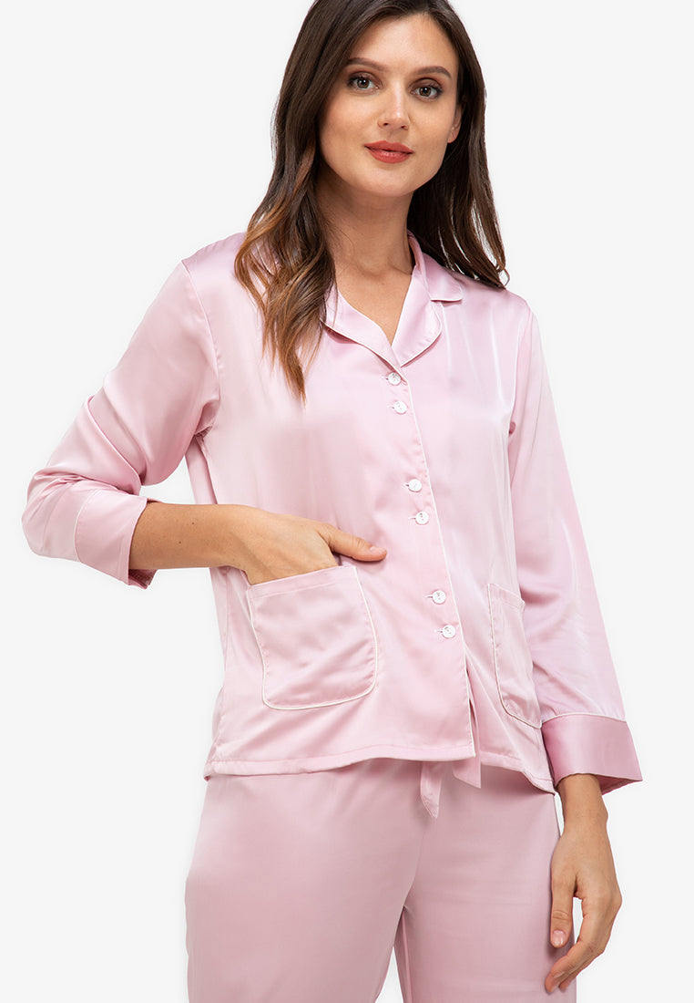A woman standing and wearing a silk long sleeve pajama set