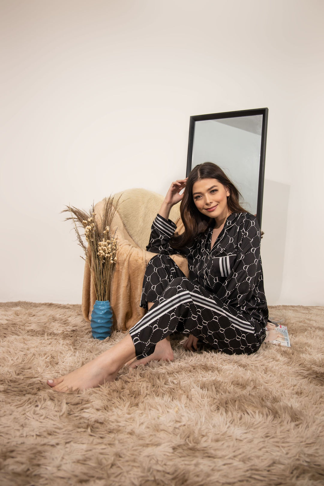 A woman sitting and wearing a collared silk long sleeve pajama set