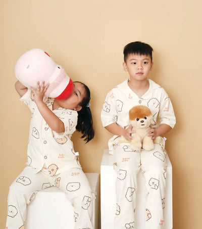 two kids wearing pajama sets holding a plush toy
