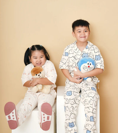 two kids wearing pajama sets holding a plush toy