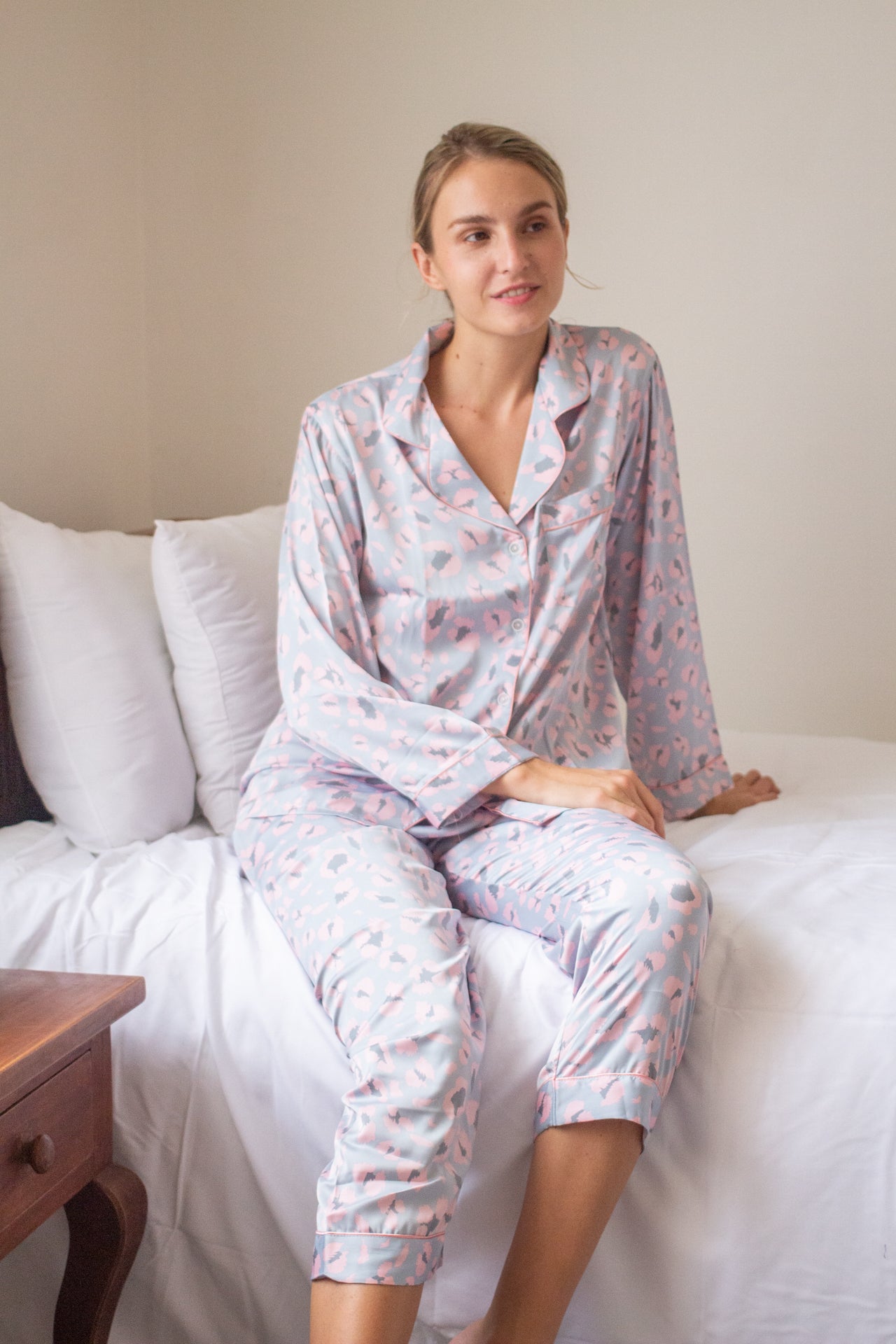 A woman sitting on the bed wearing long sleeve pajama set