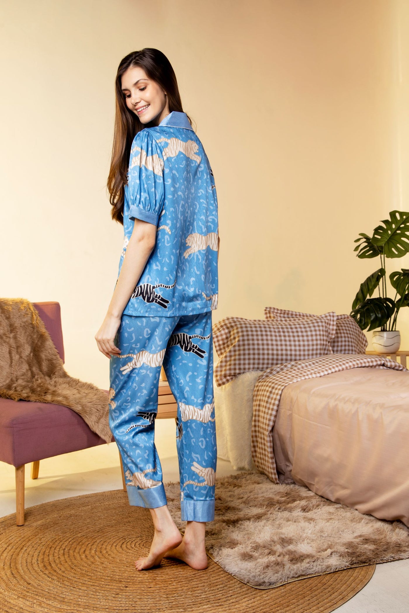 A woman standing and wearing a collared silk short sleeve pajama set