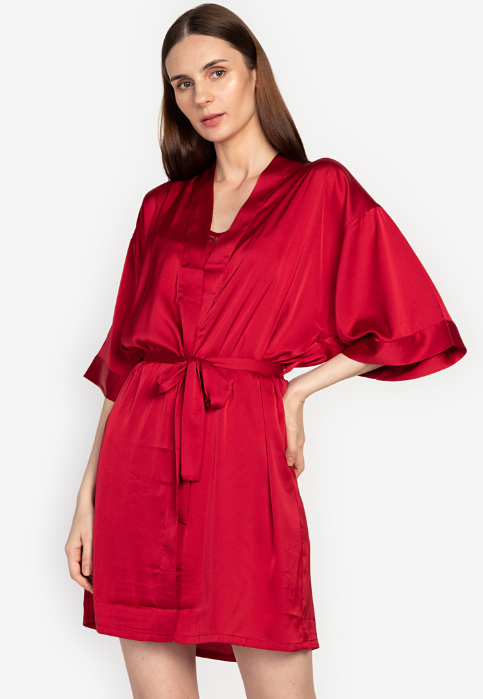 A woman standing and wearing a red Silk Romper set