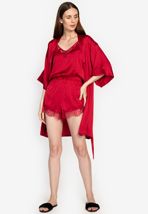 A woman standing and wearing a red Silk Romper set
