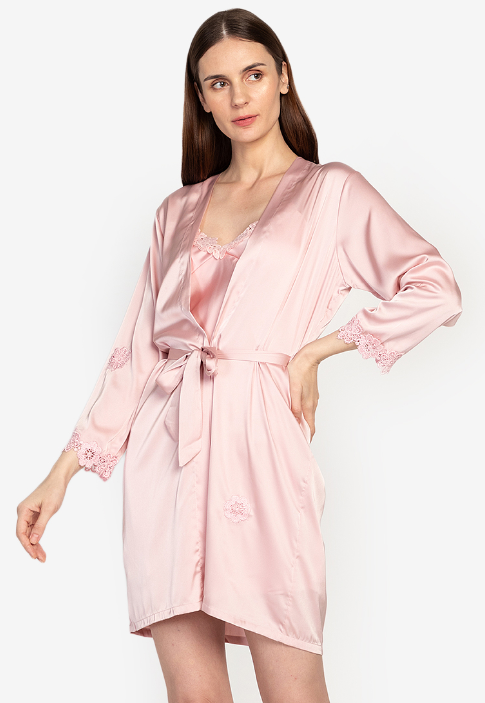 A woman standing and wearing a pink Silk Romper set