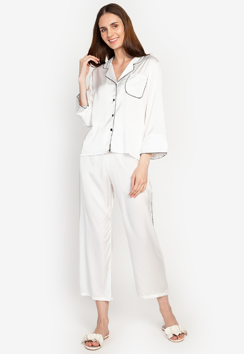 A woman wearing a silk long sleeve pajama set white