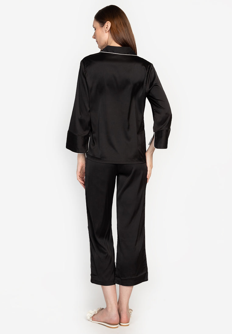 A woman wearing a silk long sleeve pajama set black