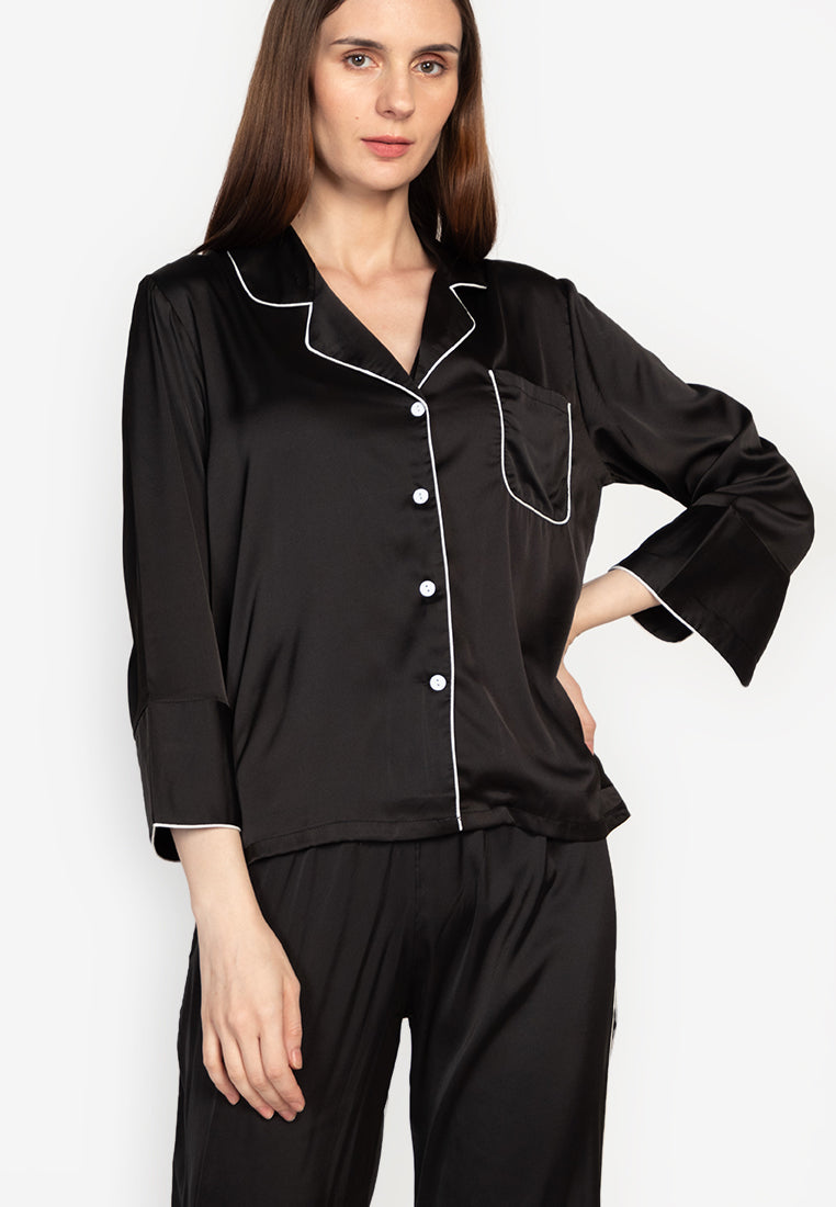A woman wearing a silk long sleeve pajama set black
