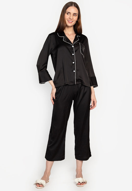 A woman wearing a silk long sleeve pajama set black