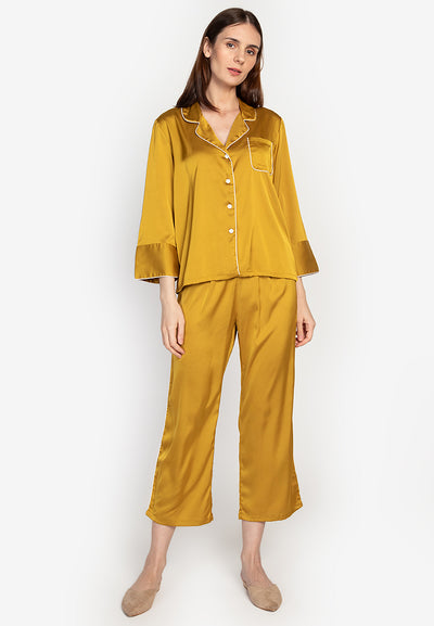 A woman wearing a silk long sleeve pajama set yellow