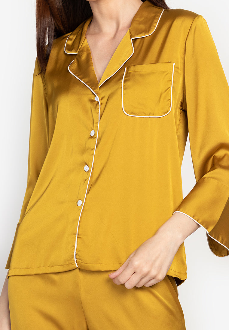 A woman wearing a silk long sleeve pajama set yellow