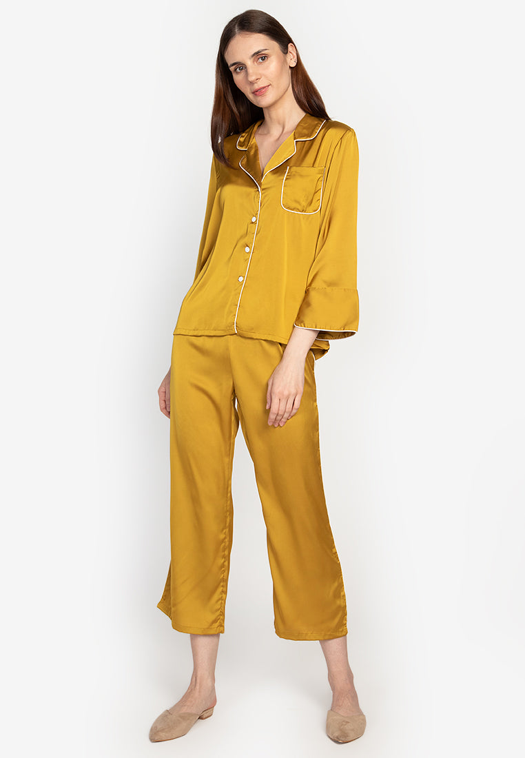 A woman wearing a silk long sleeve pajama set yellow