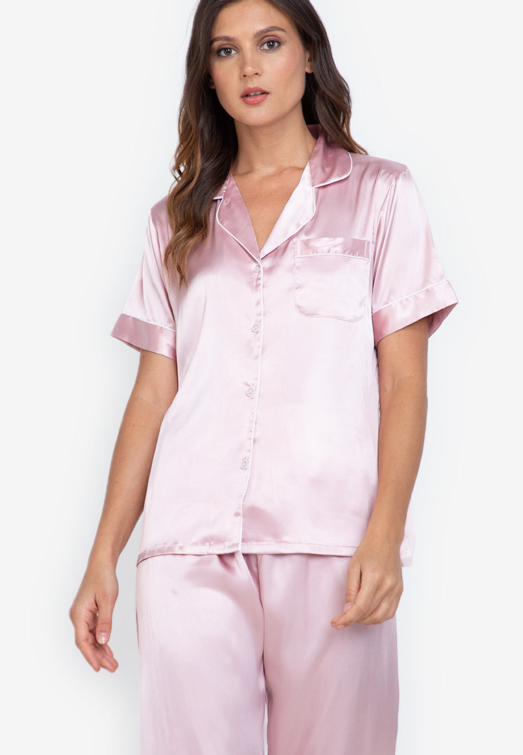 A woman standing and wearing a silk short sleeve pajama set